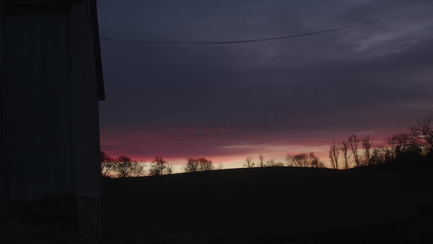 Purple sky and silhouette of trees on a farm