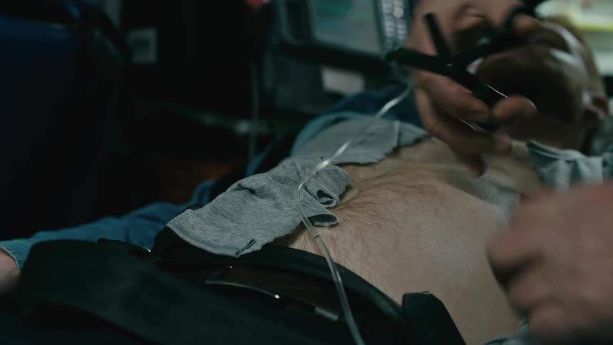 Outpatient doctor cutting the tshirt of a man who is lying on a stretcher