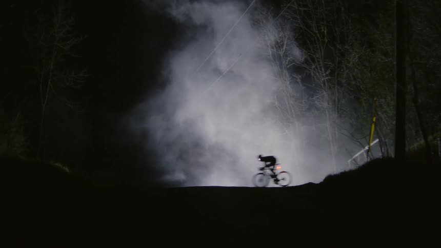 A person riding a bicycle on a foggy night