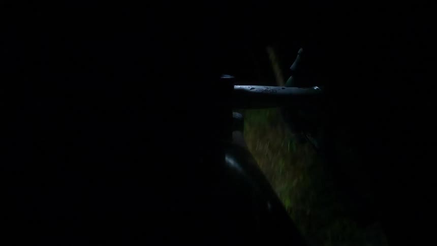 Point of view close up of the handlebars of a bicycle riding through the countryside at night