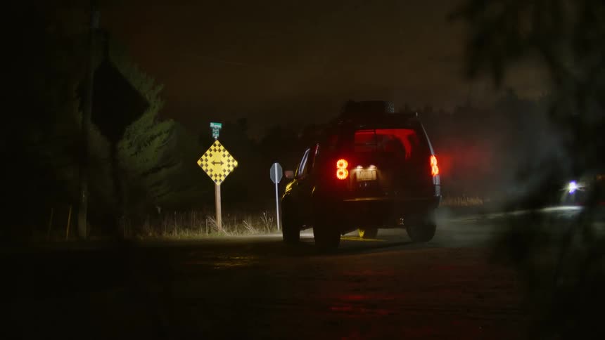 A car stopped on a deserted road in nature at night
