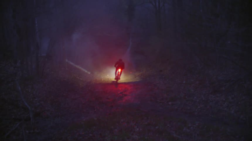 Cyclist entering an alley with access to a trail through the forest
