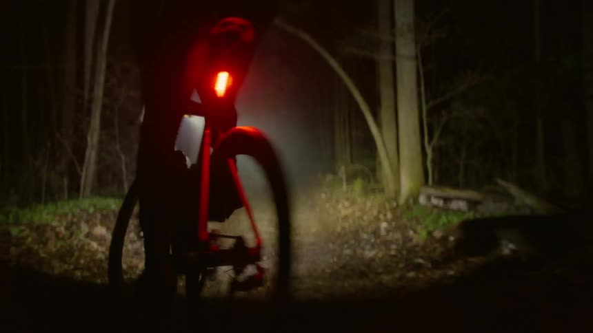 Person riding a bicycle in the woods at night