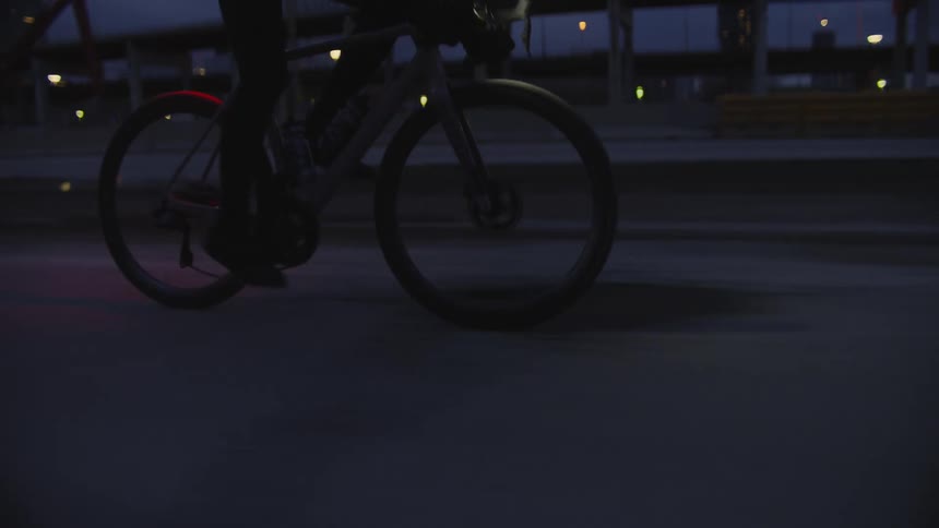 A man riding a bicycle is silhouetted against the cloudy sky
