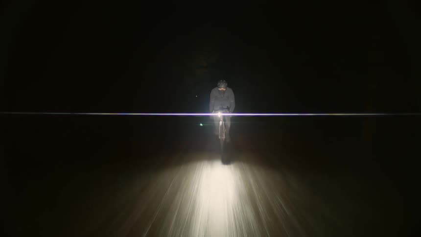 A man rides a bike on a road through a forest