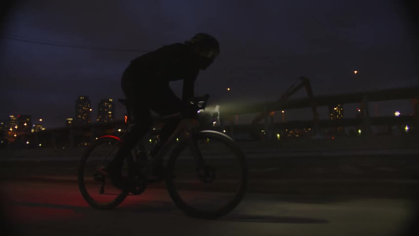 Person riding a bicycle at high speed on a city street at night