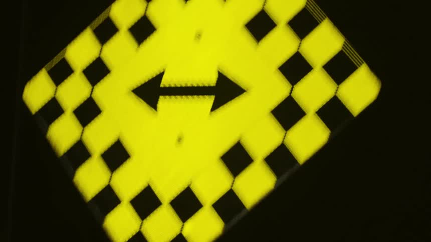 Yellow signpost being illuminated by a flashlight at night