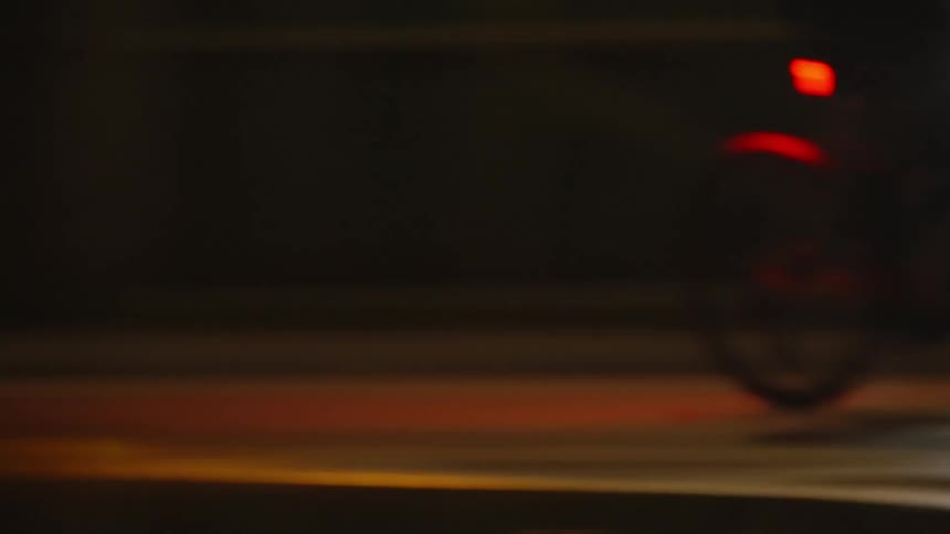Person riding a bicycle on a city road at night