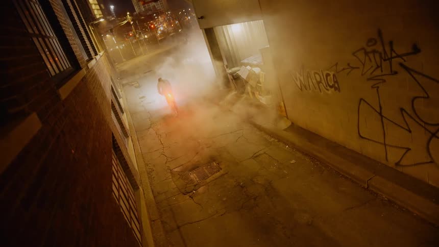 Alley of a street in a metropolitan city with a person passing by on a bicycle at high speed at night