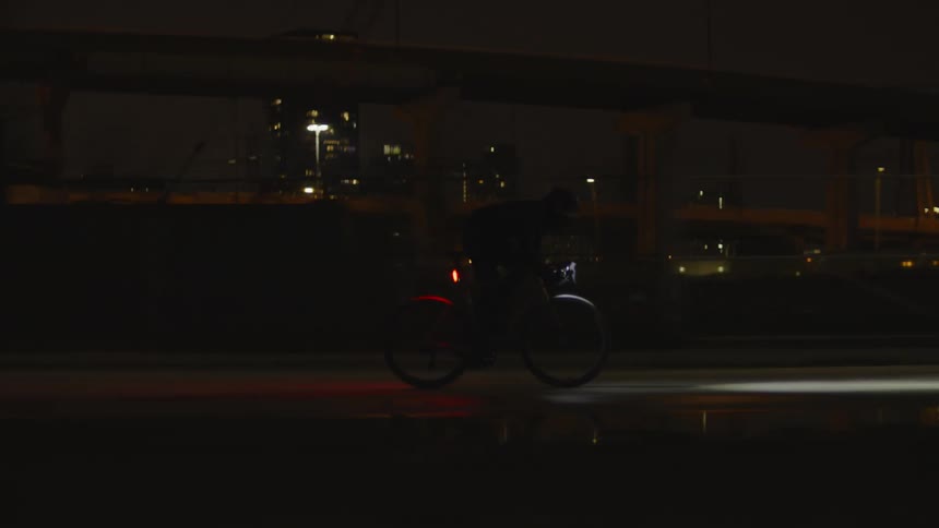 Man riding a bicycle at night in the middle of the city at high speed