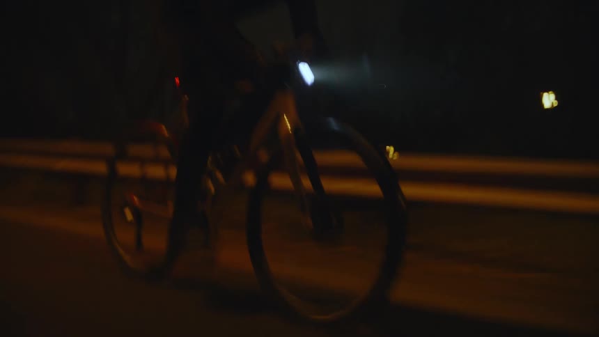 A man is racing his bike on the road at night