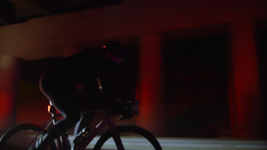 A man rides is bicycle past a police car on the road