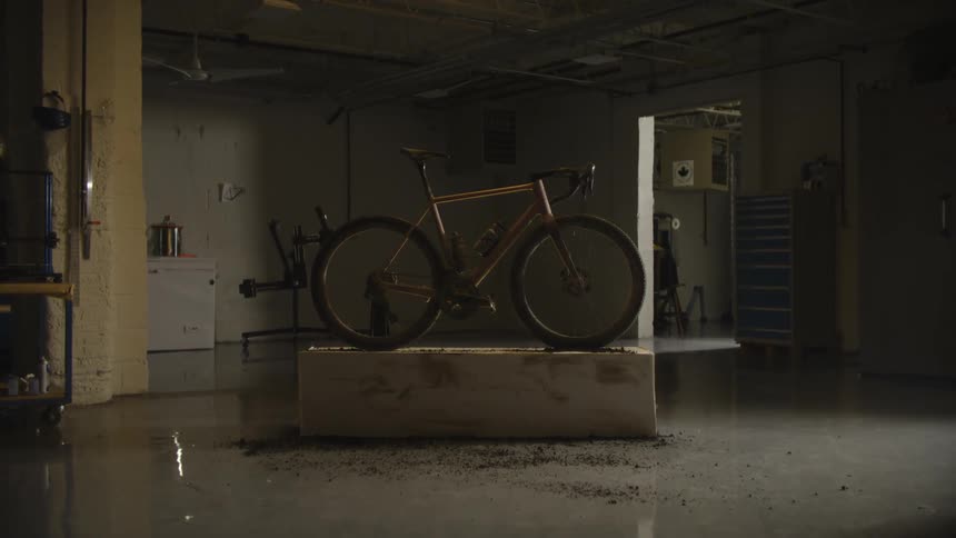 A bicycle is mounted on a platform in a dimly lit spacious garage