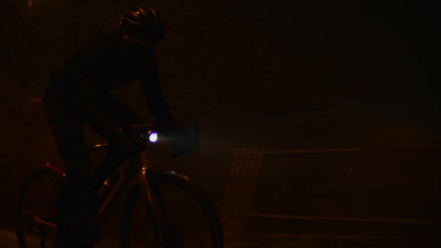 Silhouette of a person riding a bicycle quickly at night