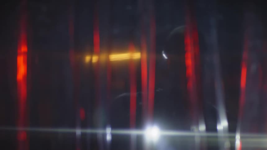 Hooded man with a flashlight opening a transparent curtain
