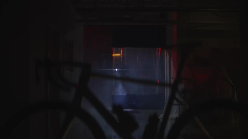 A person walking through the dark house looking for his bicycle