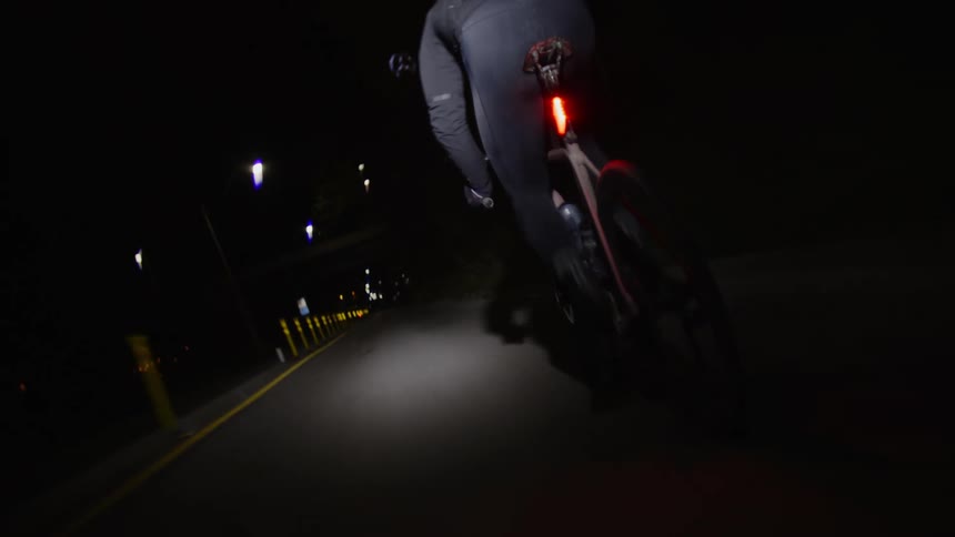 A cyclist riding his bike on a deserted city street at night