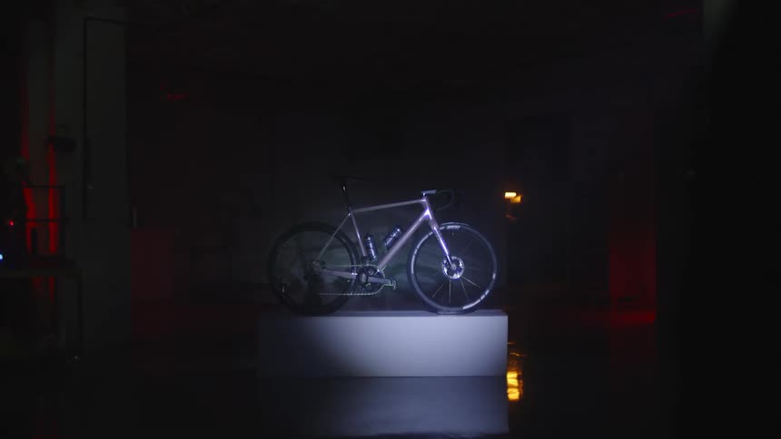Man walking inside a dark room with a flashlight and viewing a silver bicycle