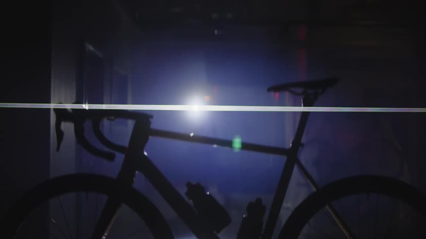 A person searching a room with a flashlight finds a bicycle