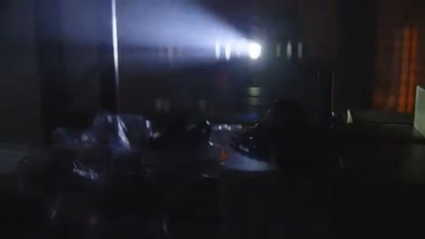 A person walking in a dark laboratory with a flashlight
