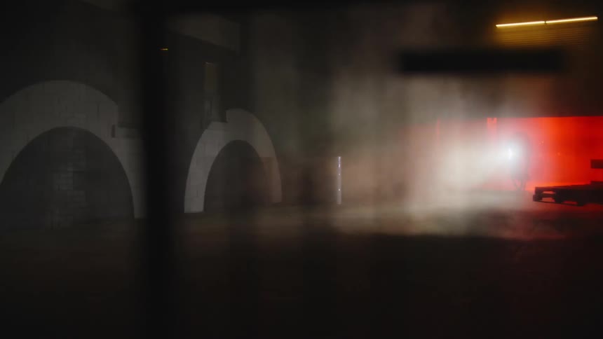 A person driving a bicycle out of a garage with flashing orange lights at night