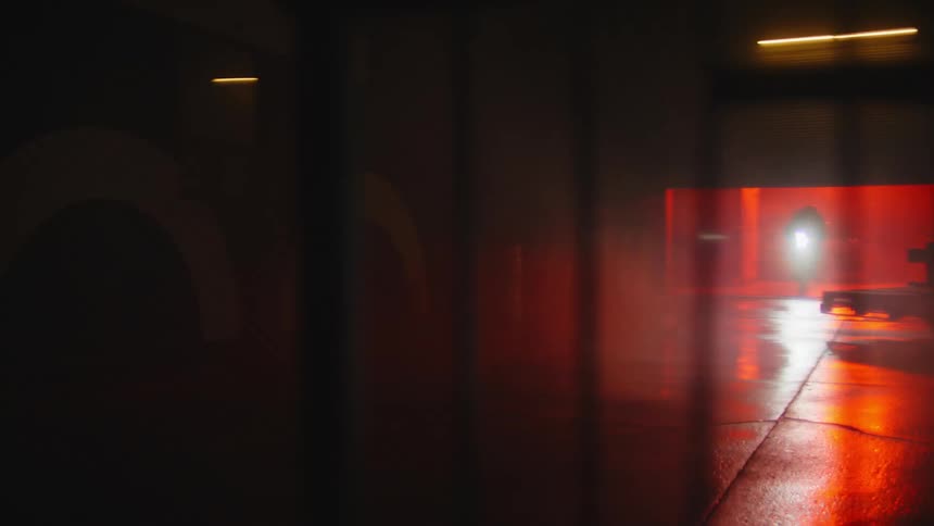 A person riding a bicycle inside a dimly lit parking garage with orange flashing lights