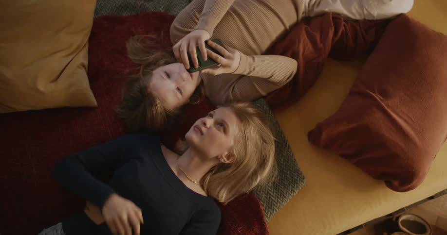 Portrait of a young man and woman lying on the couch with a young little girl both playing on their cell phones