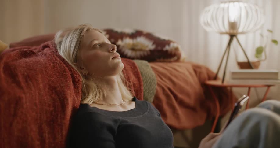 Teenage girl sitting at the side the bed with a phone in her hands