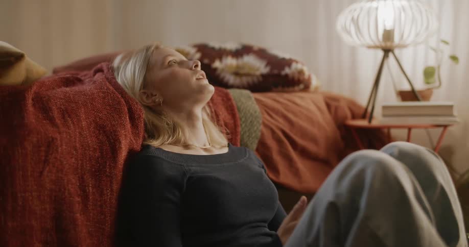 Young woman texting on her phone reclined against the bed