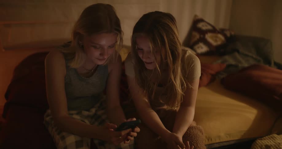 Two girls looking at something on a phone and laughing