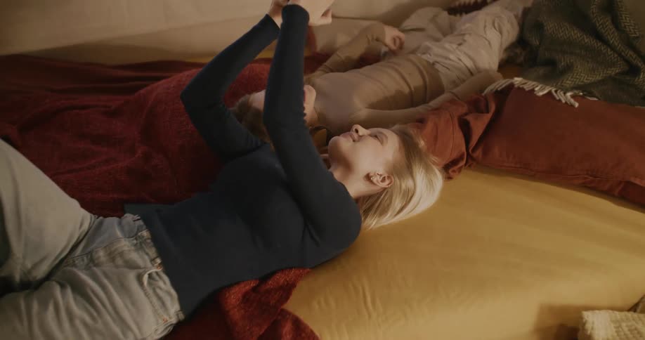 Two teenage girls have fun with a phone in the bedroom
