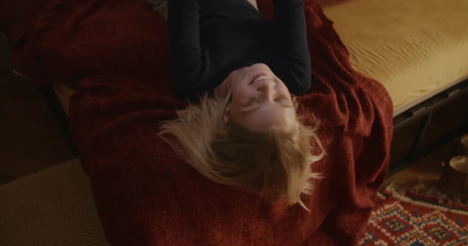 A teenager smiles while looking at her phone in bed