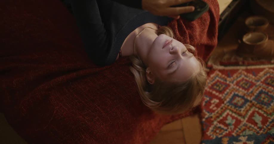 A girl resting in the bed checks her messages on her phone