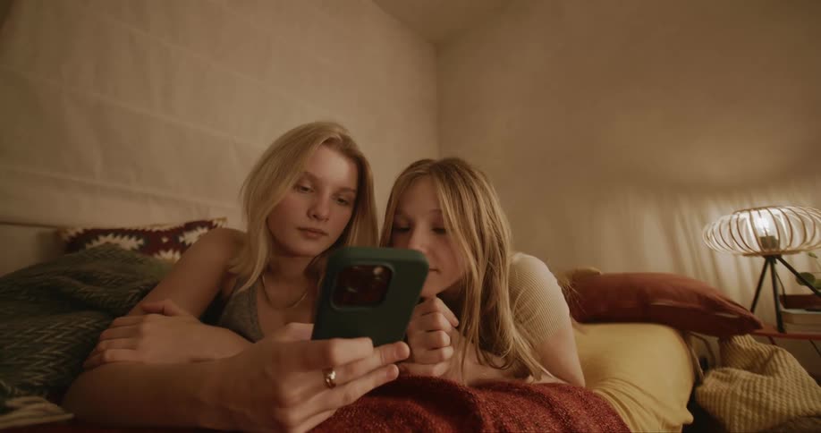 Portrait of a woman and a child both blonde using their cell phones while lying down