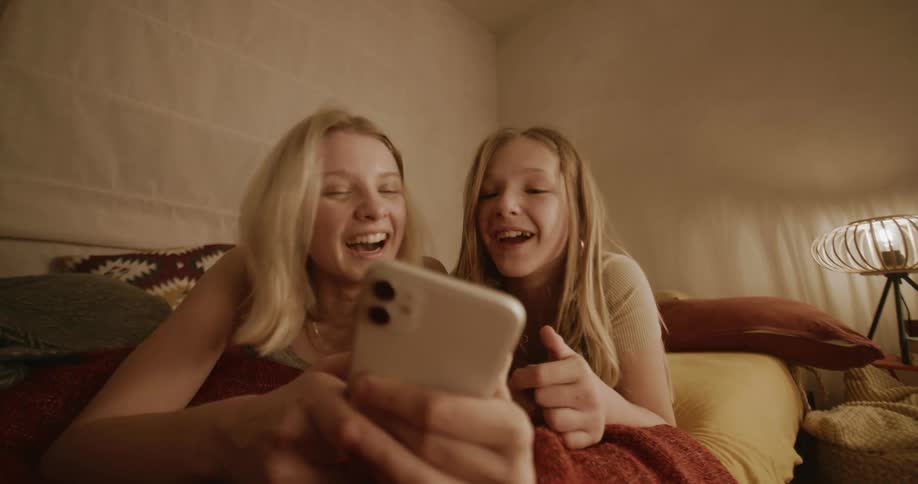 Two girls watching a video on a phone laughing