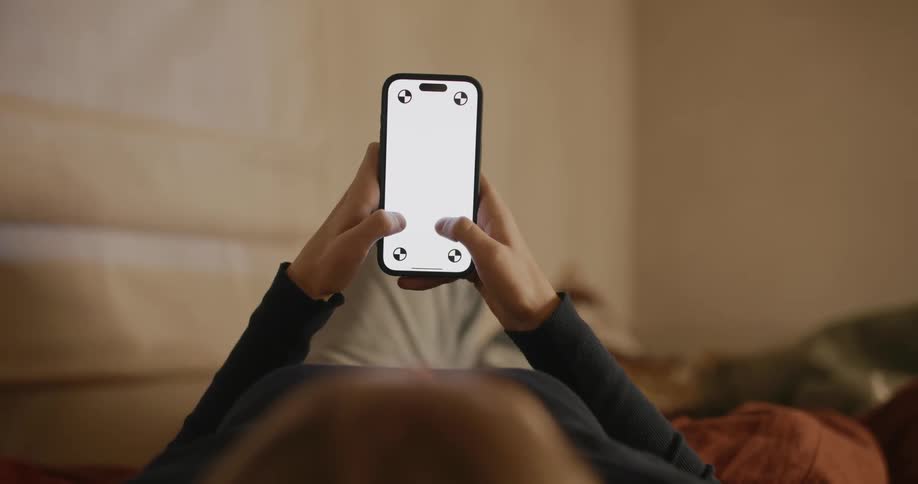 A woman lying down scrolling through a smart phone with a replaceable screen image