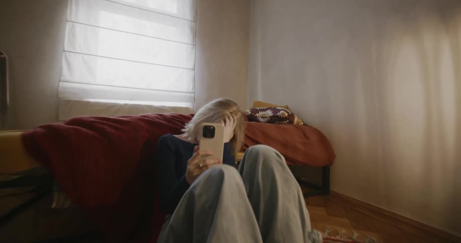 A woman laughs while looking at her cell phone