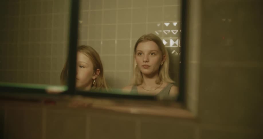Woman and a girl in front of the mirror in the bathroom looking at themselves and dancing