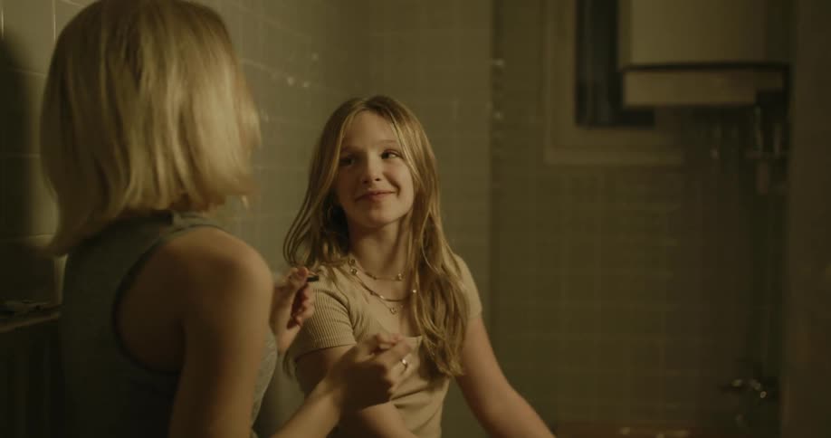 Two teenage girls laughing and playing while one of them puts makeup on the other