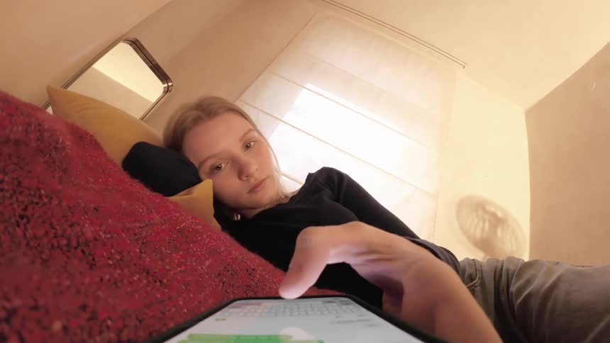 A girl typing on a cell phone lying on the bed in her room