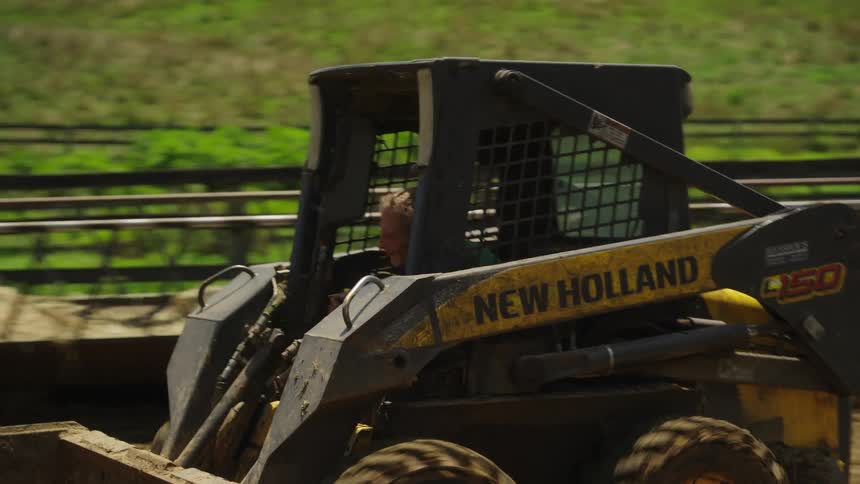 Man driving a mini tractor in the middle of a farm