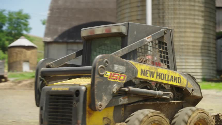 Man driving a small tractor in the middle of a farm