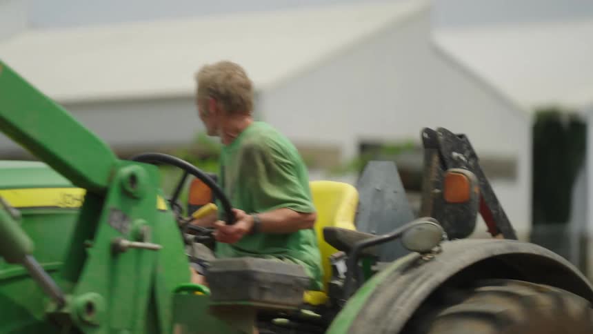 A farmer operating a green bulldozer in the farm