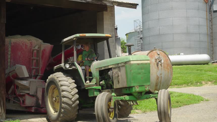 Man maneuvering an agriculture tractor and guarding it inside a ranch