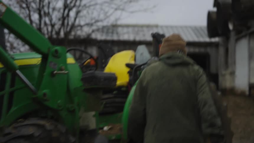 A man driving a tractor full of hay on a farm