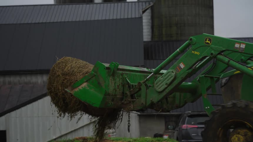 A man carries a roll of hay with a bulldozer