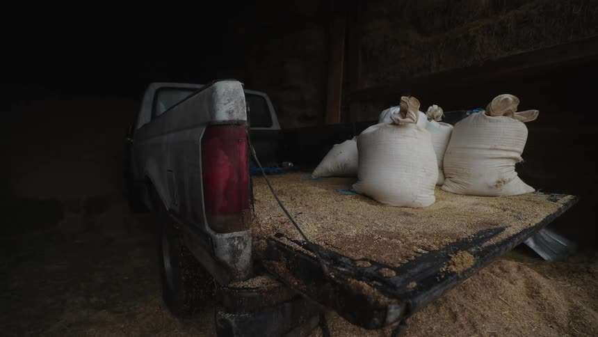 A pickup truck with bags of hay in the garage