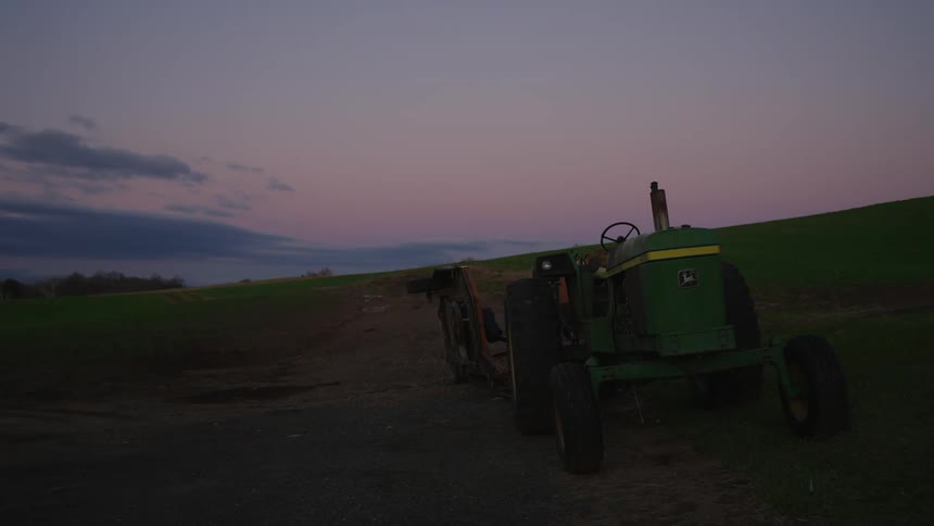 Green tractor parked on a dirt road in the field