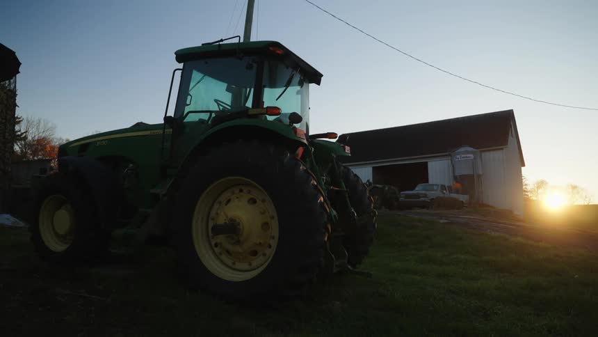 A tractor on a farmland at sunset
