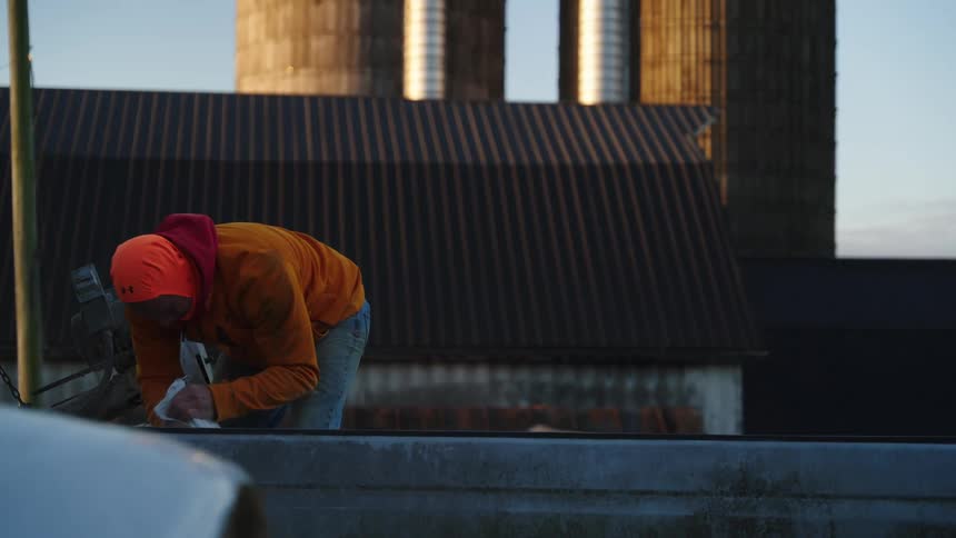 Person seals bag near shed with two narrow towers in the background